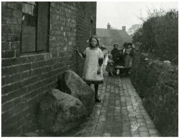 B+W image of Child with 2 anvil stones in Sandbank backyard